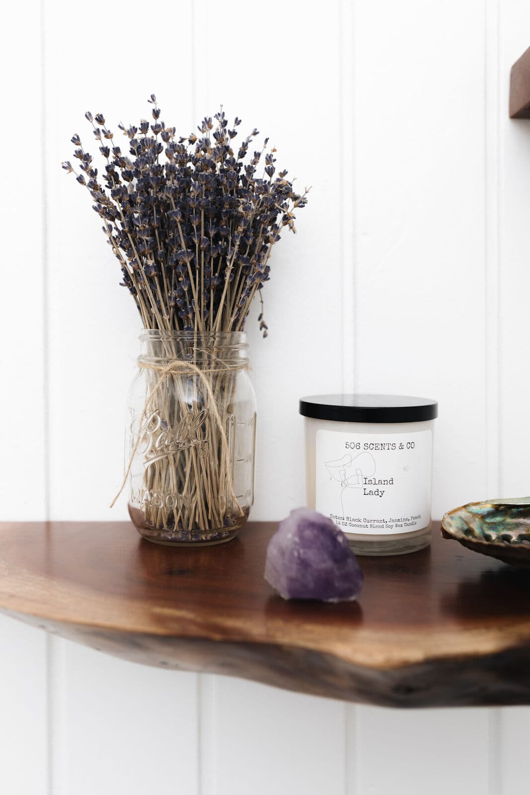 Dried lavender and a candle on a wooden shelf