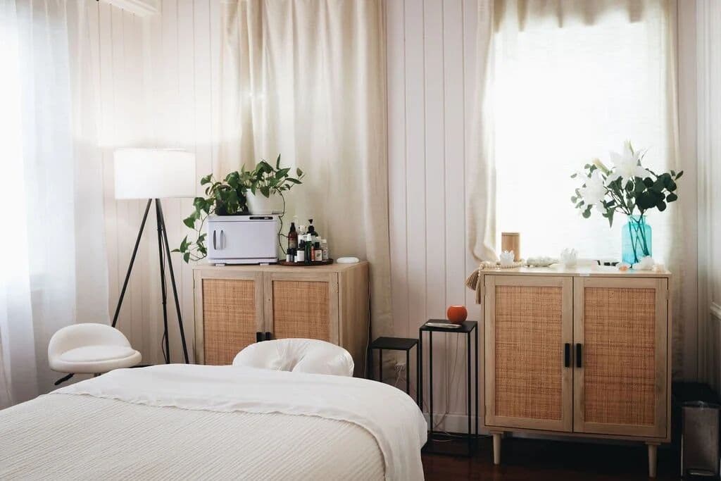 A sunlit treatment room with rattan cabinets